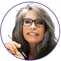 woman with glasses holding a paint brush